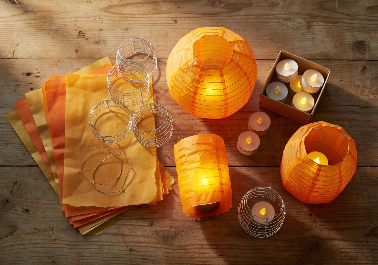 Seasonal paper lantern kit with tissue paper, wire frames, battery tea lights and completed glowing lanterns in amber tones